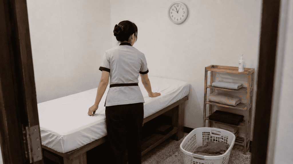 พนักงานสปาจัดเตียงและผ้าสะอาดระหว่างรอบบริการ