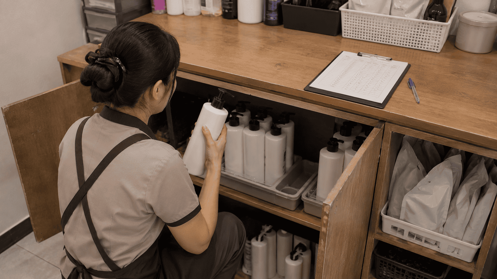 พนักงานร้านเสริมสวยตรวจนับขวดผลิตภัณฑ์เทียบกับใบตรวจสต๊อก